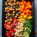 Colorful vegan Buddha bowl with tahini chickpeas, quinoa, and various roasted vegetables for a nutritious meal.